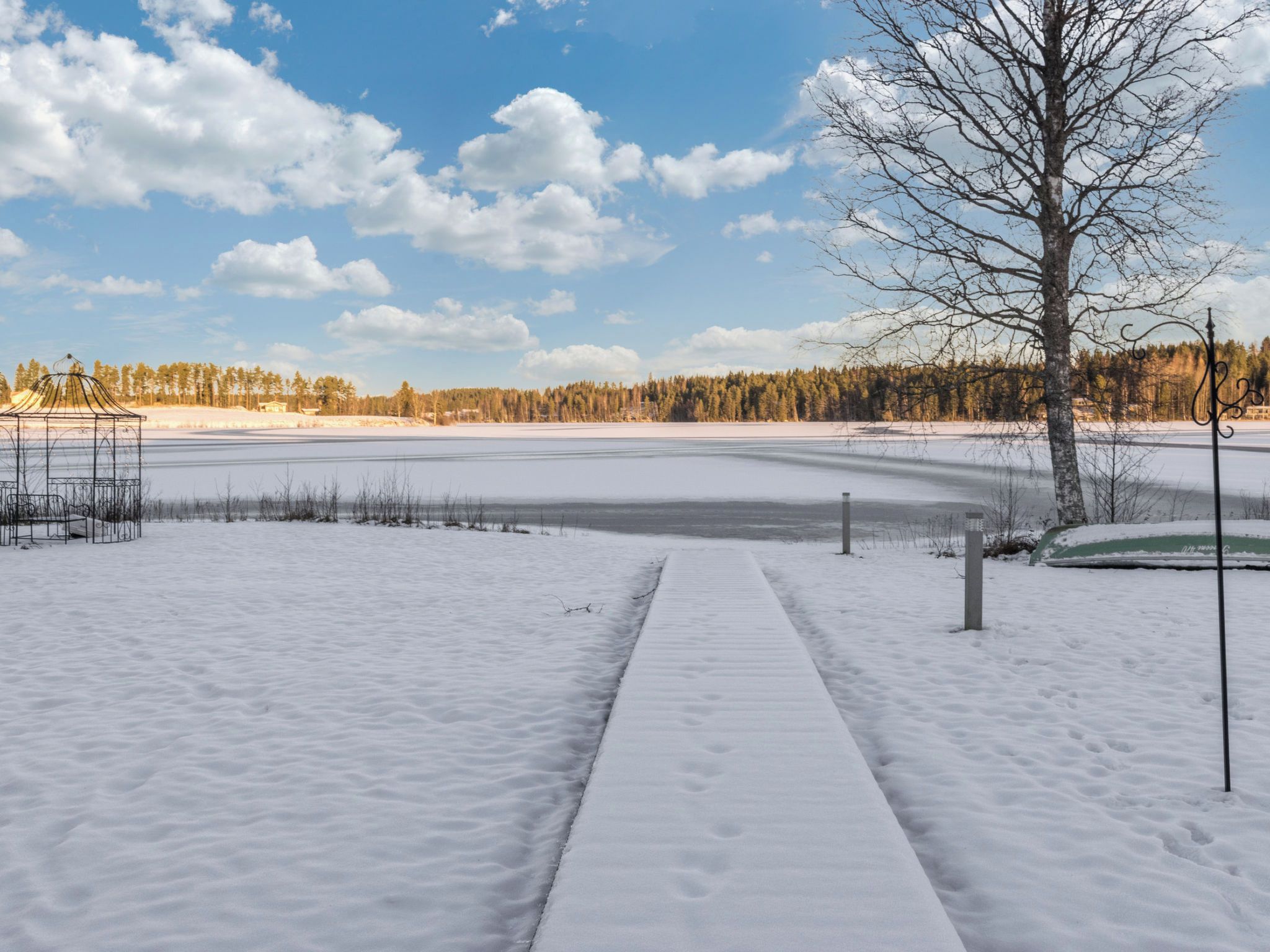 A snow-covered pathway leading to a body of water with a clear sky above.