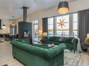 Una sala de estar moderna con un sofá verde, una chimenea y un ventanal con decoración de estrellas.