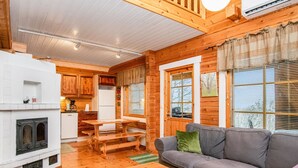L’intérieur d’un chalet chaleureux, avec une table à manger en bois, un canapé gris et une cheminée.