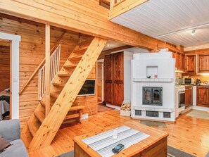 Un intérieur en bois avec un escalier, une cheminée et un coin cuisine.