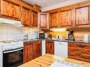 Een keuken met houten kastjes, een fornuis, een magnetron en een vaatwasser.