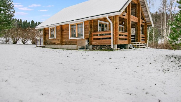 Une cabane en bois avec un toit à deux versants, de grandes fenêtres et une véranda couverte.