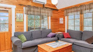 A cozy cabin interior with a grey sofa set, a wooden coffee table, and a ceiling fan.