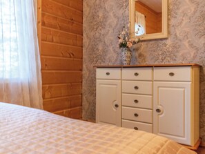 A bedroom with a bed, a dresser with drawers, a mirror, and a window with curtains. - Näsinjoutsen by Interhome (Ruovesi)