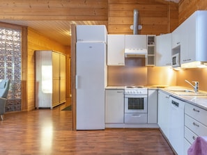 Cocina compacta con refrigerador, estufa, microondas y pileta.