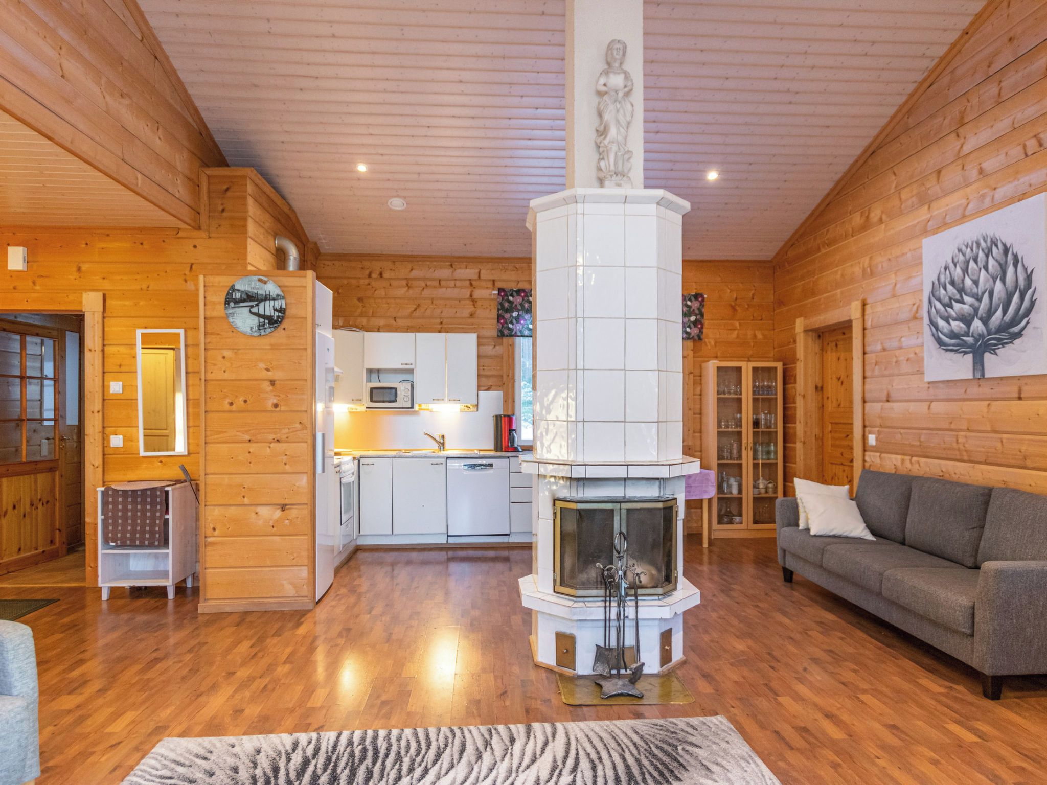 Un interior de madera con chimenea, un sofá y una zona de cocina.