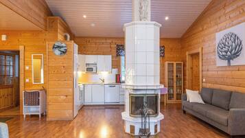 Un interior de madera con chimenea, un sofá y una zona de cocina.