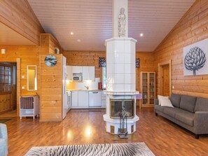 A wooden interior with a fireplace, a sofa, and a kitchen area. - Näsinjoutsen by Interhome (Ruovesi)