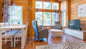 A wooden cabin interior with a dining area, seating, a television, and large windows. - Näsinjoutsen by Interhome (Ruovesi)