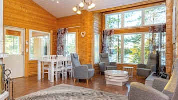 Un interior acogedor con paredes de madera, un comedor y asientos con vista a árboles.