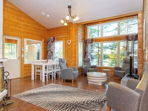 A cozy interior with wooden walls, a dining area, and seating with a view of trees. - Näsinjoutsen by Interhome (Ruovesi)