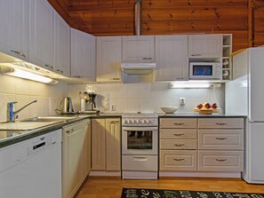 A kitchen with white cabinets, a stove, a microwave, and a dishwasher. - Näsinneito by Interhome (Ruovesi)