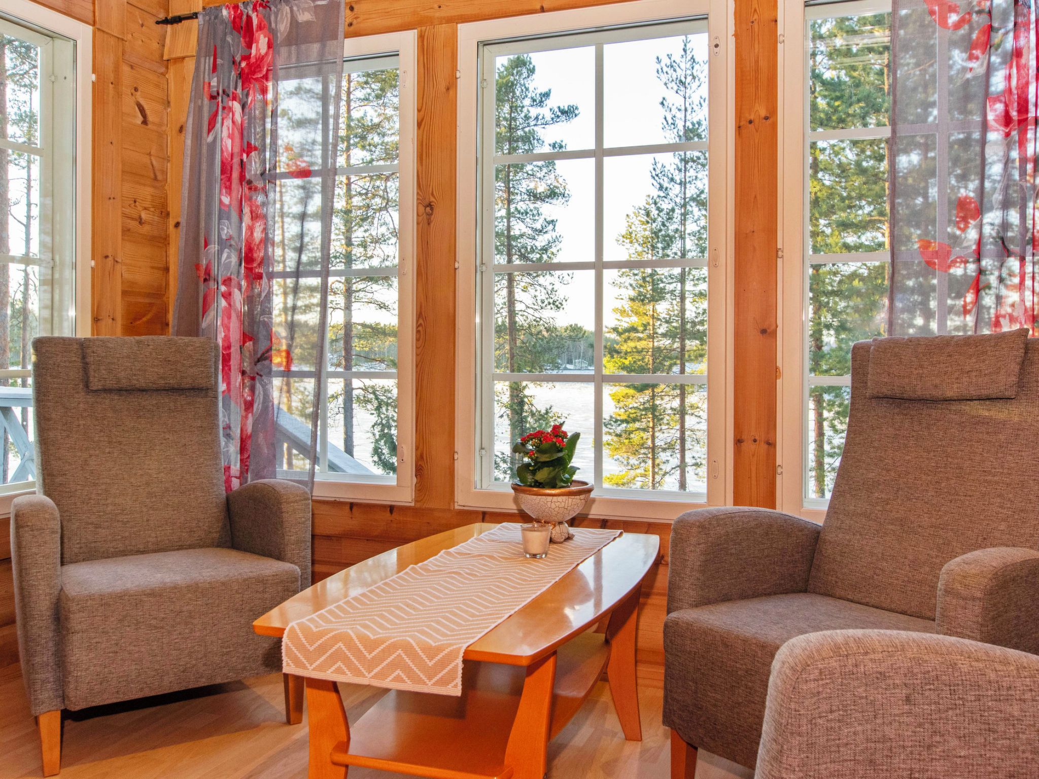 A cozy room with two armchairs, a wooden table, and large windows with curtains.