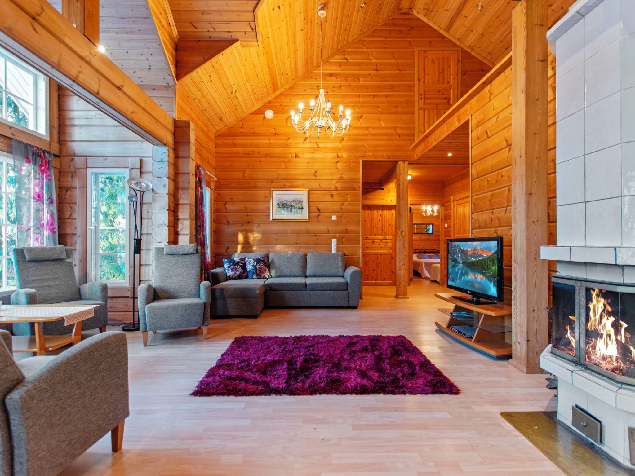 Ein gemütliches Blockhaus-Interieur mit Kamin, Fernseher und einer bequemen Sitzecke.