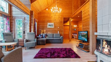 Ein gemütliches Blockhaus-Interieur mit Kamin, Fernseher und einer bequemen Sitzecke.