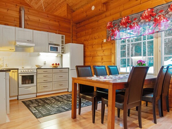 A wooden interior with a kitchen, dining table, and chairs.