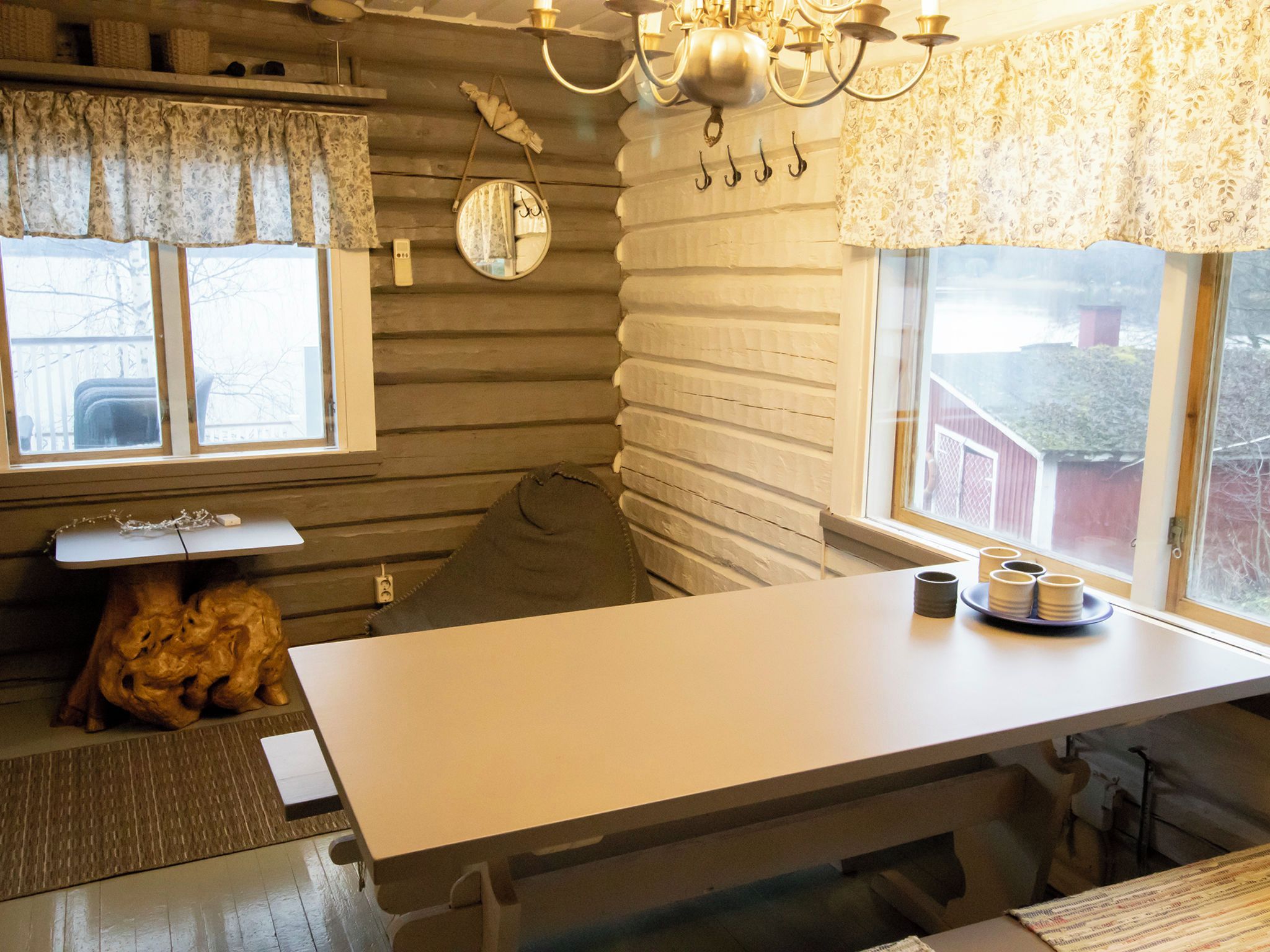 A compact kitchen with a wooden wall, a table, and a window with curtains.