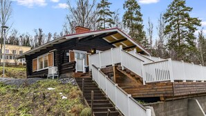 A log cabin with a wooden staircase leading to a deck.
