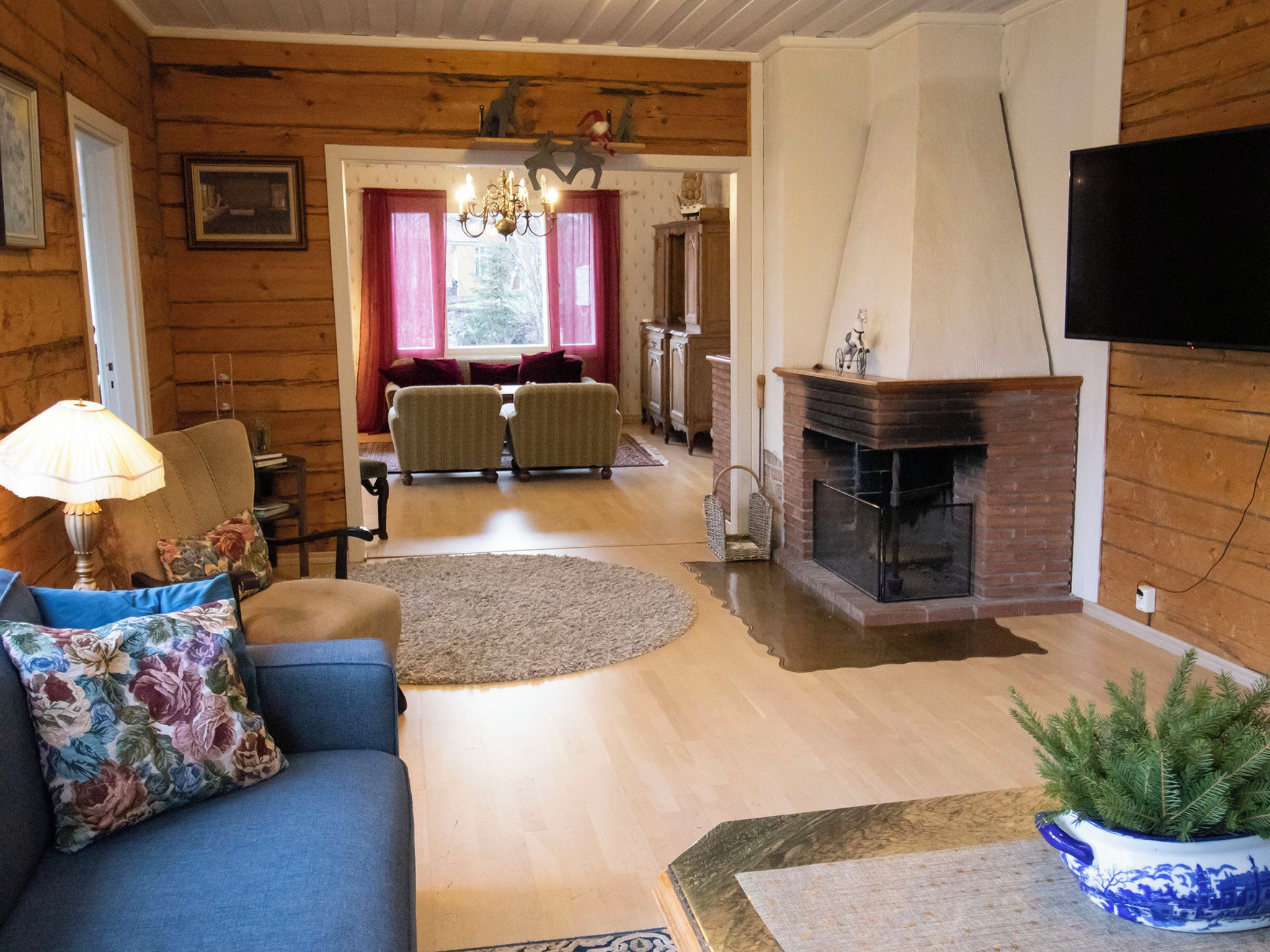 A cozy living room with a fireplace, a sofa, a television, and a dining area with two chairs.