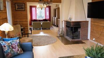 A cozy living room with a fireplace, a sofa, a television, and a dining area with two chairs.