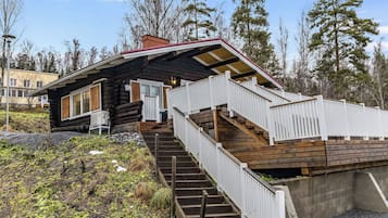 Hirsimökki, jossa on puinen portaikko, joka johtaa terassille.
