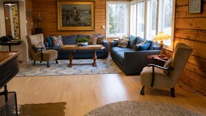 A cozy living room with wooden walls, a blue sofa, a dark armchair, and a coffee table.