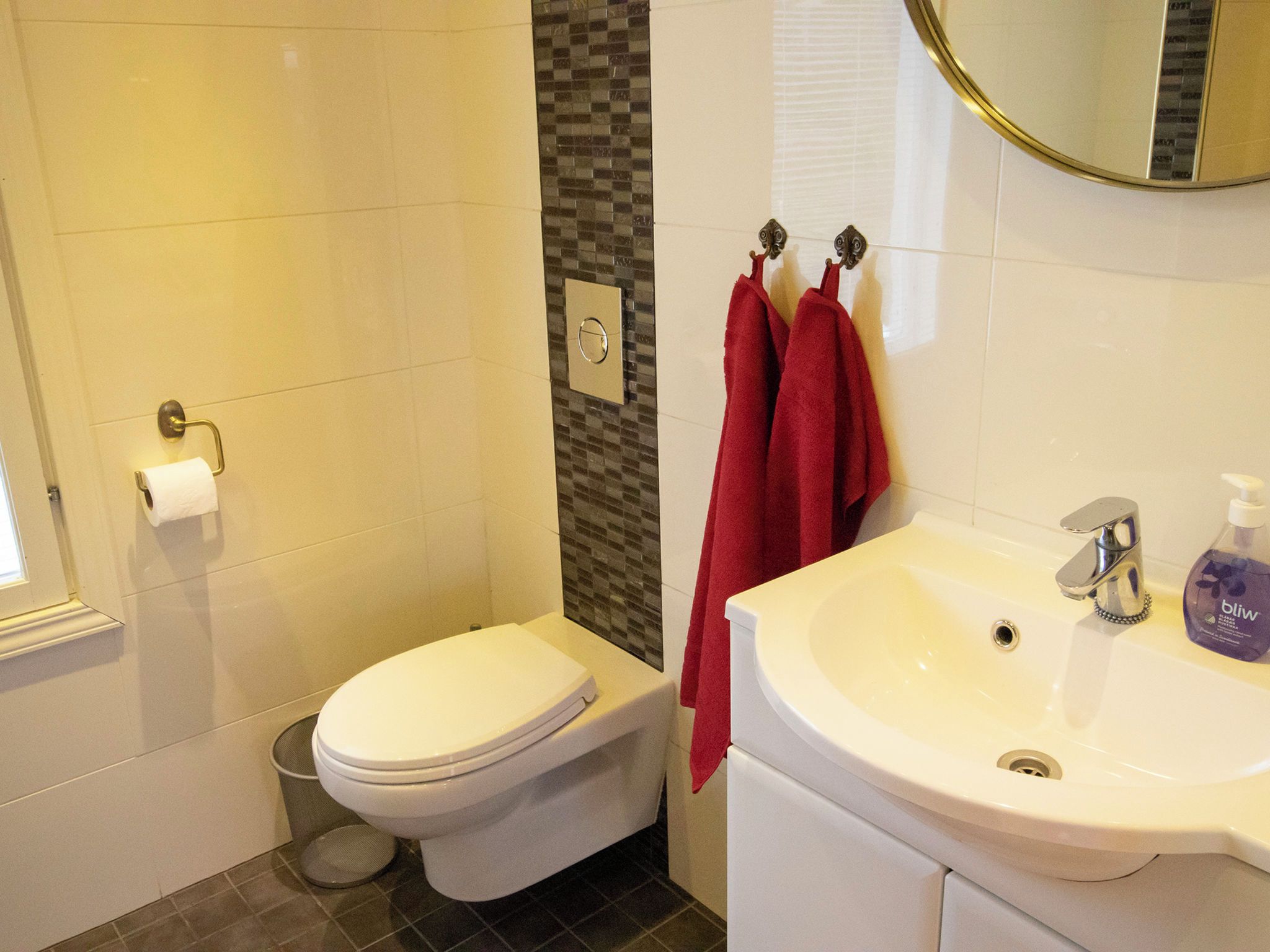 A bathroom with a toilet, a sink, a mirror, and a towel rack.