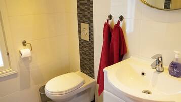 A bathroom with a toilet, a sink, a mirror, and a towel rack.