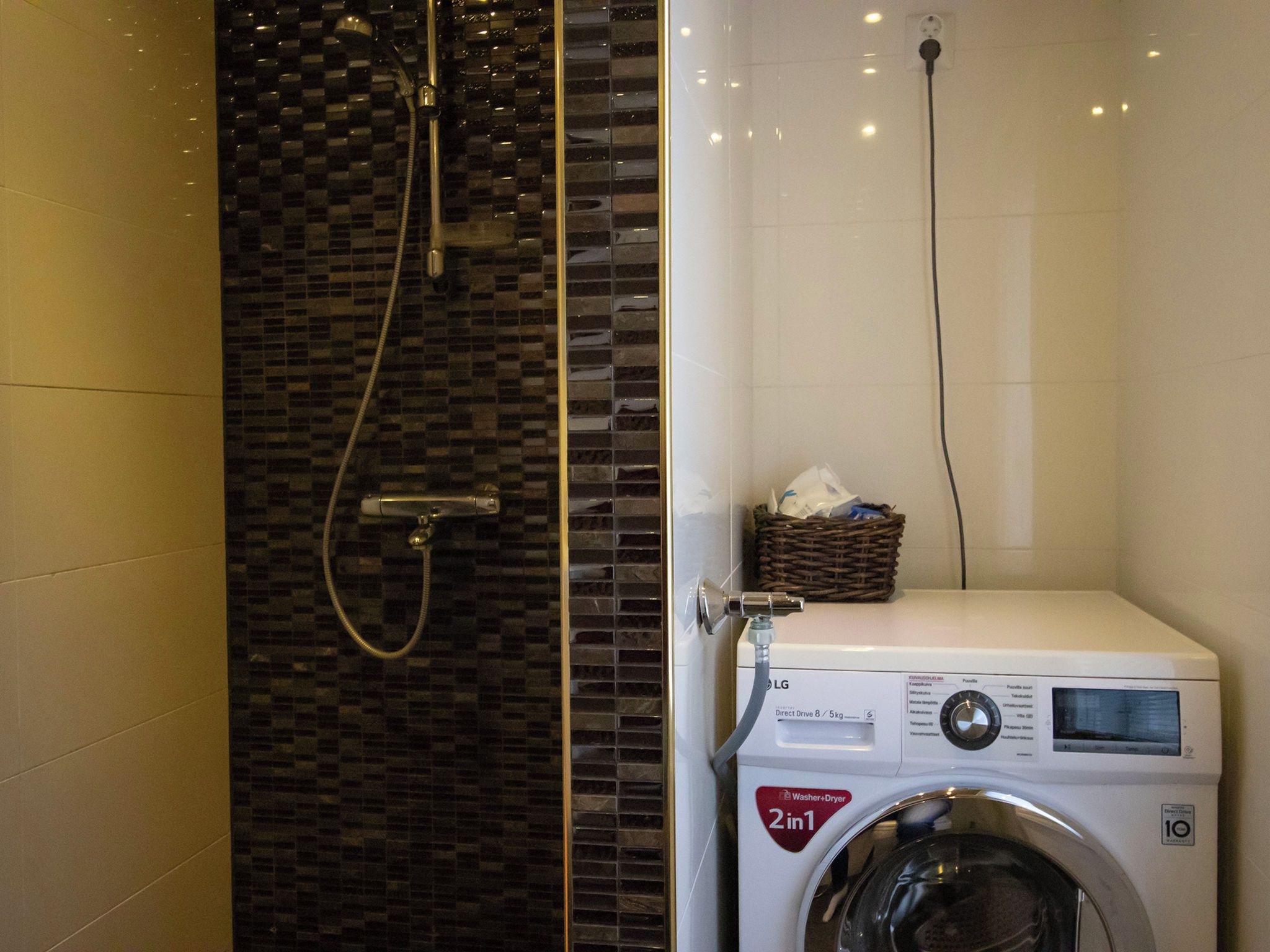 A compact bathroom with a washing machine and a shower.