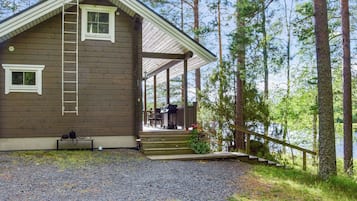 Eine Holzhütte mit Veranda, einer Leiter und einem Schotterweg.