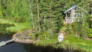 Una cabaña rodeada de un bosque frondoso y un lago.