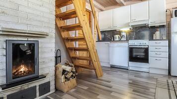 A modern kitchen with white cabinets, a wooden staircase, and a fireplace.