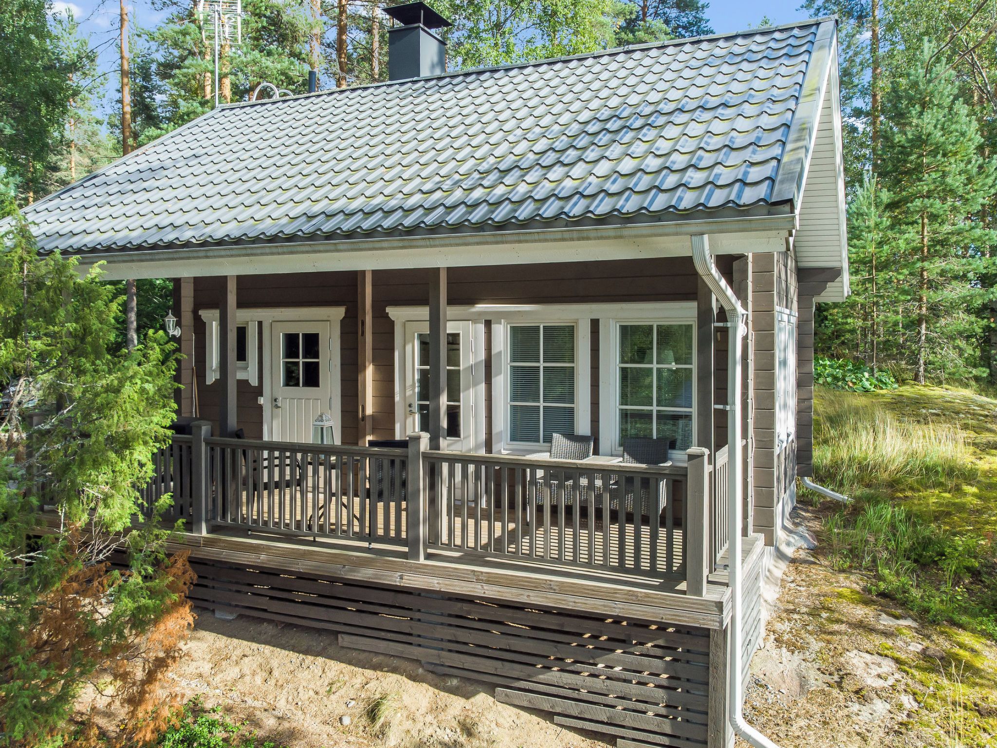A cabin with a covered porch, a chimney, and a deck.