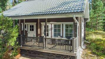 A cabin with a covered porch, a chimney, and a deck.