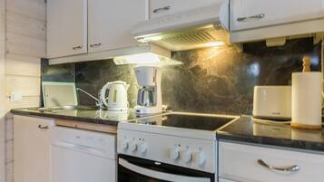 Cocina con gabinetes blancos, estufa, cafetera y salpicadero de mármol.