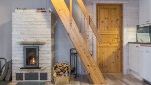 Una habitación con chimenea, una escalera de madera y una zona de cocina.