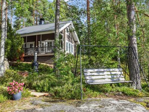 A cabin with a porch, surrounded by dense forest.