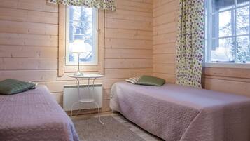 Ein gemütliches Zimmer mit zwei Betten, einem kleinen Tisch und einem Fenster mit Vorhängen.