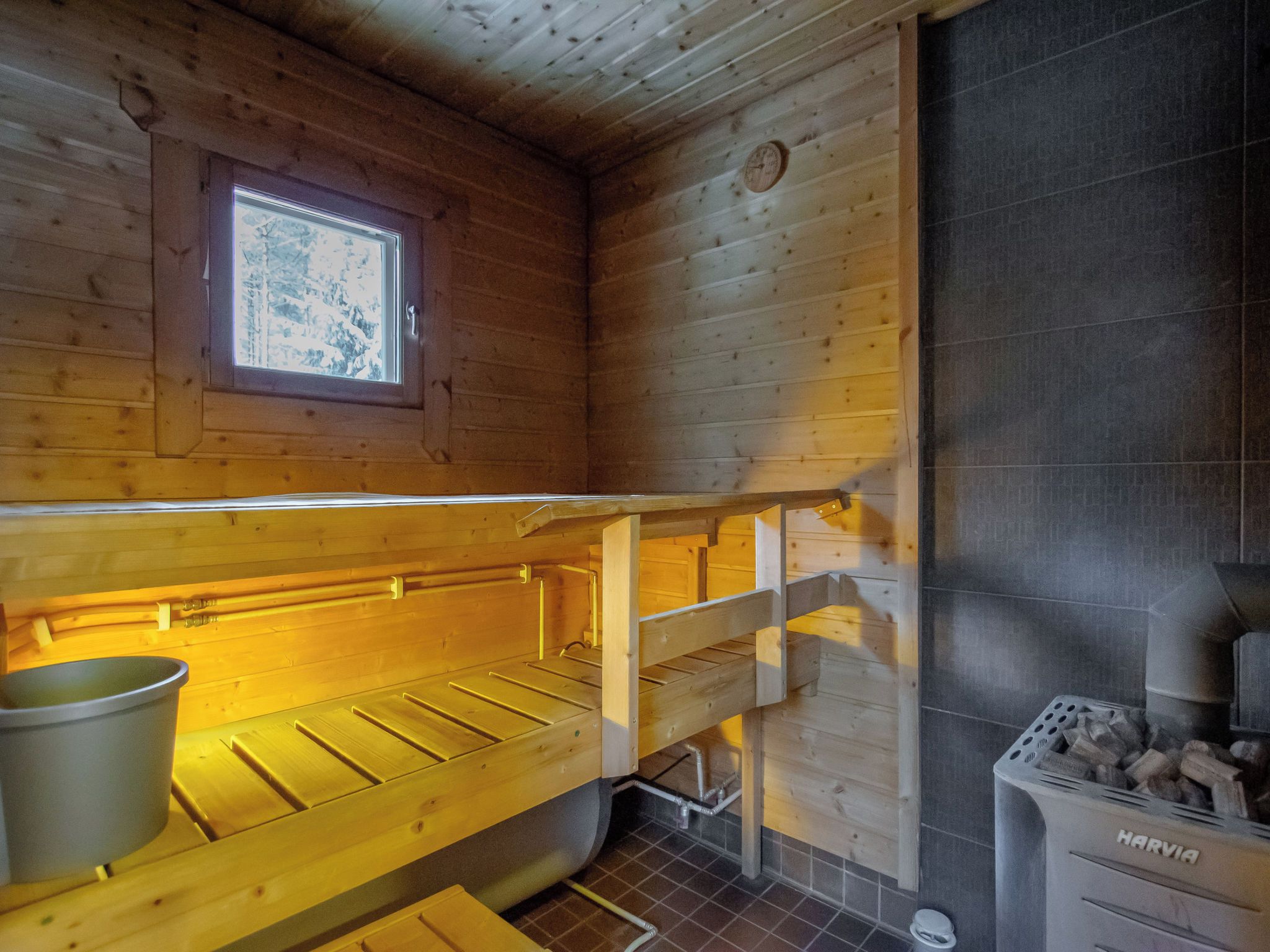 Ein Holzblockhaus-Interieur mit Etagenbett, Fenster, Kamin und Herd.