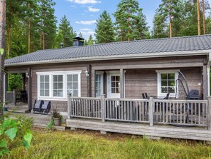 Une cabane dotée d’une véranda, d’un espace salon extérieur et offrant une vue sur la forêt environnante.