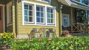 Ein Haus mit einer Veranda, einem Essbereich mit Stühlen und einem Garten mit verschiedenen Pflanzen.