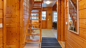 Interior de madera con una escalera central, paredes de madera y vistas al exterior.