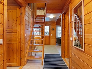 A wooden interior with a central staircase, a sofa, and a view of the outside.