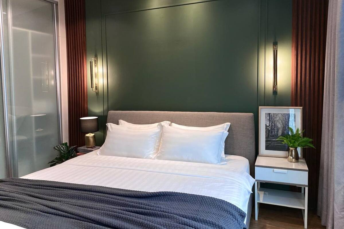 A modern bedroom with a large bed, a bedside table, a lamp, and a framed picture on the wall.