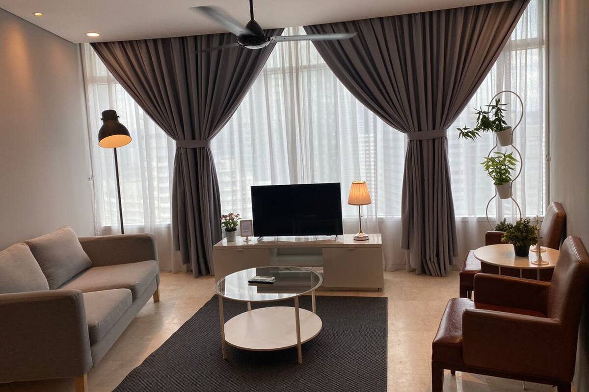 A modern living room with a sofa, coffee table, TV, and a ceiling fan.