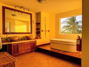 Enjoy a relaxing soak in the large oval bathtub, paired with a spacious vanity and a view of palm trees.