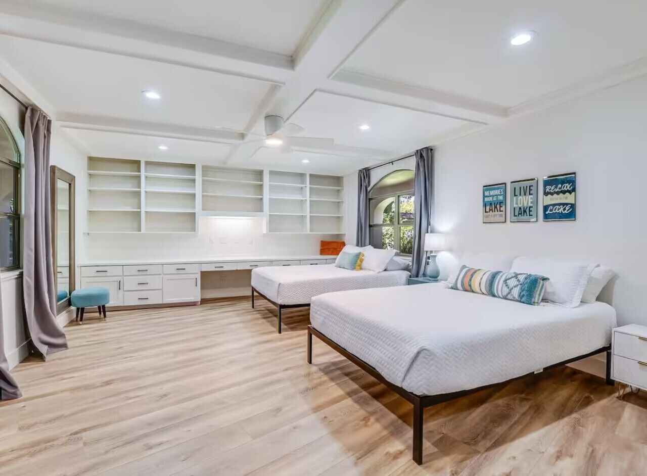 Une chambre moderne avec deux lits, un bureau et une grande fenêtre.