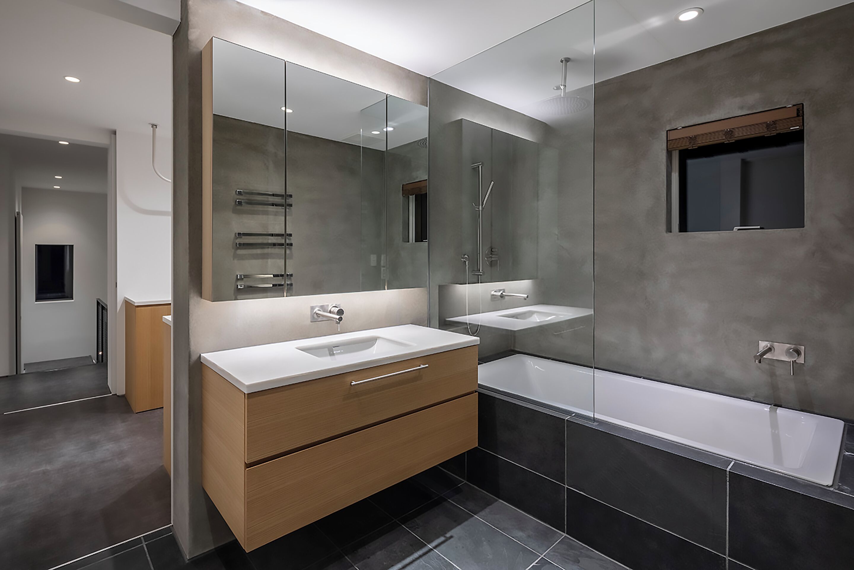 A modern bathroom with two sinks, a large mirror, and a bathtub.