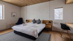 A modern bedroom with a large bed, a wooden ceiling, a desk, and a chair.
