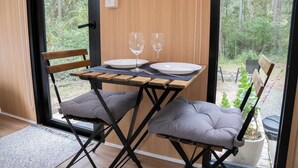 Un coin repas avec une table dressée pour deux personnes, deux verres à vin et deux assiettes.